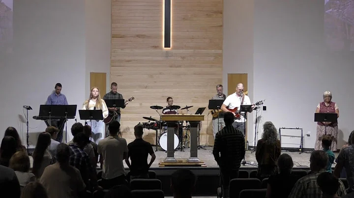 The Lawson Baptist congregation stands for worship with musicians beneath the sanctuary’s wood cross backdrop.